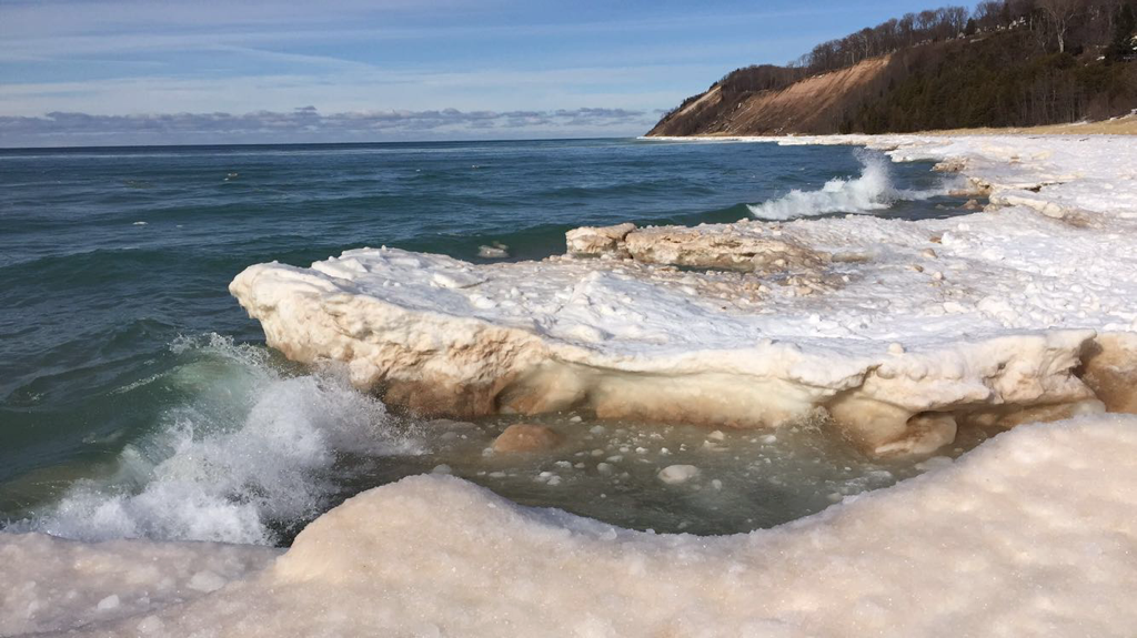 Lake Michigan waves break on the icy beach in Frankfort, Michigan on a sunny winter morning.