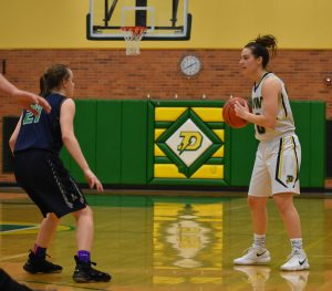 Junior Maizie Taylor looks to pass in a game against Lapeer High School as a major distributor for the girls varsity basketball team. Taylor has started on the varsity team since her freshman year and is highly regarded for her ability to share the ball. Photo by Alix Campbell